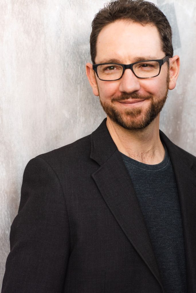 About Jeremy Jeremy smiling in front of a light gray background. Photo: Pepperfox Photo